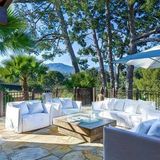 Auf der Terrasse stehen weiße Sitzmöbel. Man hat einen herrlichen Blick in die grüne Umgebung.