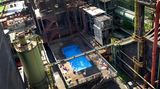 Es ist das wohl ungewöhnlichste Freibad Deutschlands: das Werksschwimmbad der Zeche Zollverein in Essen, das mitten in die Reste der ehemaligen Kokerei montiert wurde. Für den Badespaß haben Frankfurter Künstler zwei Überseecontainer aneinandergeschweißt und auf ein Holzgestell gesetzt. Das dient nun als Liegewiese.