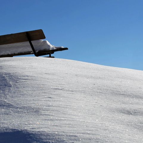 Eine Parkbank steht im Schnee. Während der Hitzewelle soll es in Köln schneien.