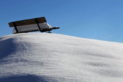 Eine Parkbank steht im Schnee. Während der Hitzewelle soll es in Köln schneien.