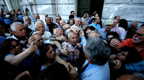 Ein Mitarbeiter der National Bank of Greece wird von Rentnern überwältigt, als er Wartenummern für die Geldschalter verteilt