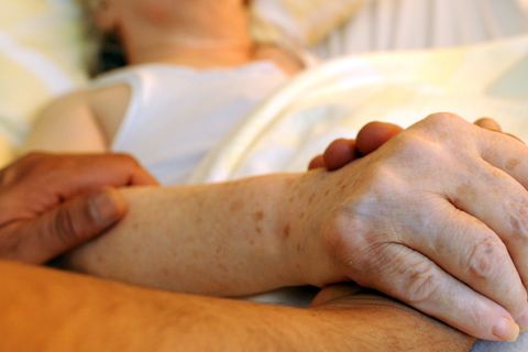 Ein Pfleger hält die Hand einer Frau