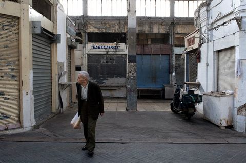 Griechischer Rentner vor verfallenen Häusern