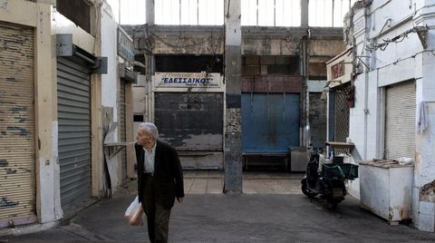 Griechischer Rentner vor verfallenen Häusern