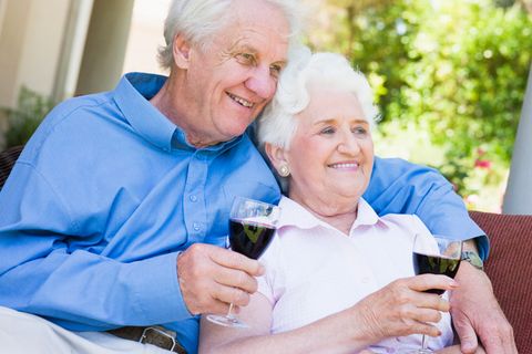 Ein altes Ehepaar sitzt auf der Terrasse und trinkt Rotwein