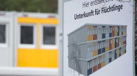 (Symbolbild) Ein Schild weist in Berlin Köpenick auf eine Wohnanlage hin, die eine Flüchtlingsunterkunft werden soll