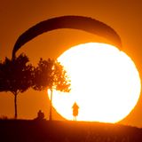 Freizeitsportler warten bei der derzeitigen Hitze besser bis in die Abendstunden, ehe sie joggen, radeln - oder eben paragleiten. Dieser Gleitschirmflieger übt am Kronsberg in Hannover beim Sonnenuntergang das sogenannte Groundhandling, die Kontrolle des Schirms am Boden.