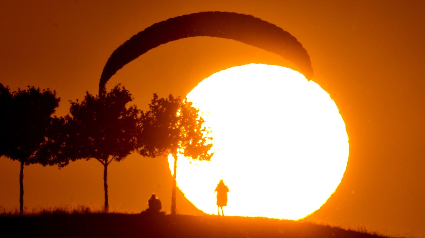 Der Sommer in Bildern: Freizeitsportler warten bei der derzeitigen Hitze besser bis in die Abendstunden, ehe sie joggen, radeln - oder eben paragleiten. Dieser Gleitschirmflieger übt am Kronsberg in Hannover beim Sonnenuntergang das sogenannte Groundhandling, die Kontrolle des Schirms am Boden. Freizeitsportler warten bei der derzeitigen Hitze besser bis in die Abendstunden, ehe sie joggen, radeln - oder eben paragleiten. Dieser Gleitschirmflieger übt am Kronsberg in Hannover beim Sonnenuntergang das sogenannte Groundhandling, die Kontrolle des Schirms am Boden.
