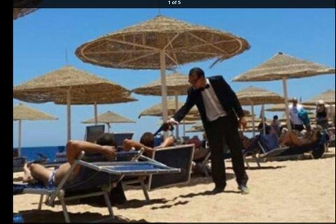 Hotelmitarbeiter im James-Bond-Look zielt mit einer Plastikpistole auf Urlauber