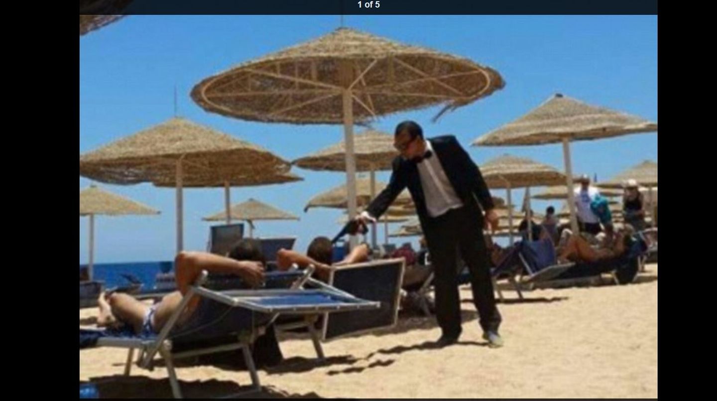 Hotelmitarbeiter im James-Bond-Look zielt mit einer Plastikpistole auf Urlauber