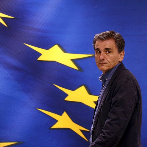 Euklid Tsakalotos steht vor einer Projektion der griechischen und europäischen Flagge