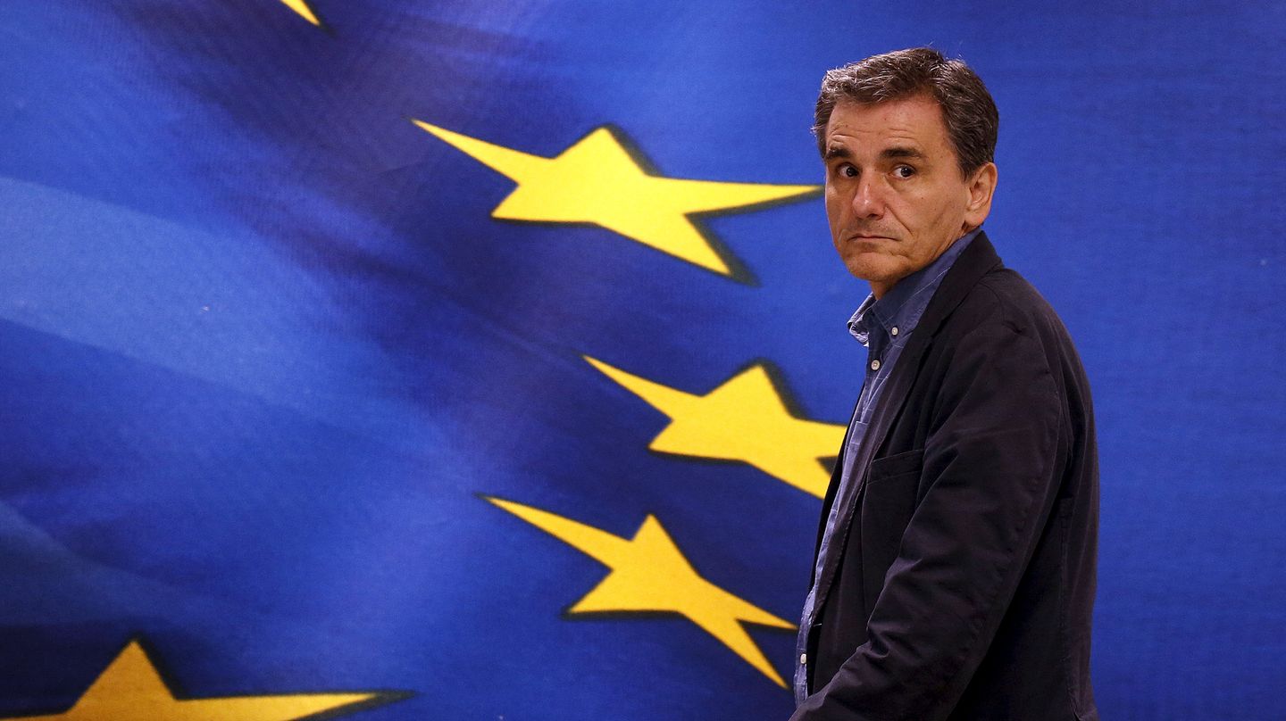 Euklid Tsakalotos steht vor einer Projektion der griechischen und europäischen Flagge