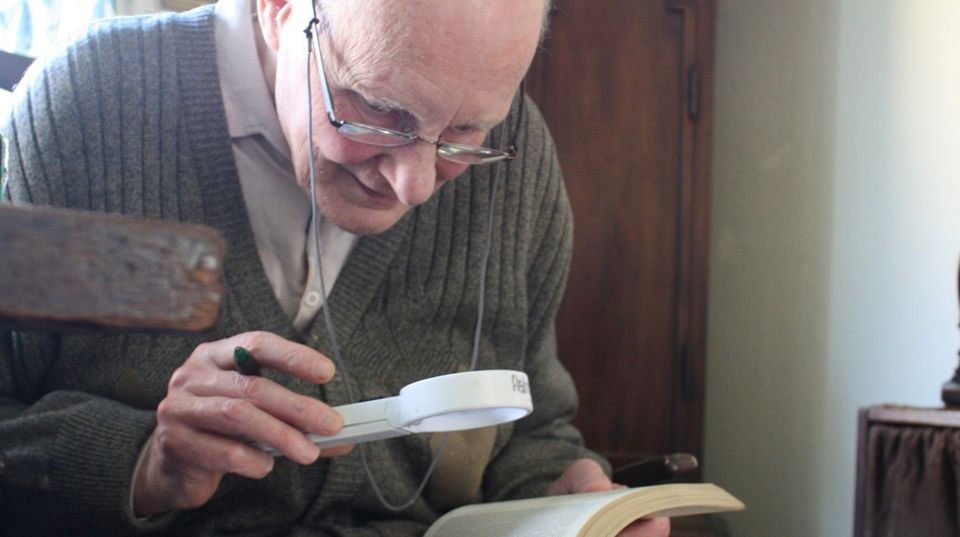 Eberhard hält eine Lupe in der Hand und liest ein Buch Eberhard hält eine Lupe in der Hand und liest ein Buch