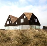 Das Dune House wirkt, als ob das Dach über dem voll-verglasten Erdgeschoss schweben würde.