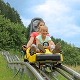 Eine Frau und ein Mädchen sausen die Sommerrodelbahn Gutach hinab