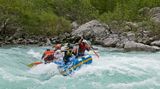 Beim Rafting auf der Saalach paddeln sechs Männer in einem Schlauchboot durchs Wildwasserr.