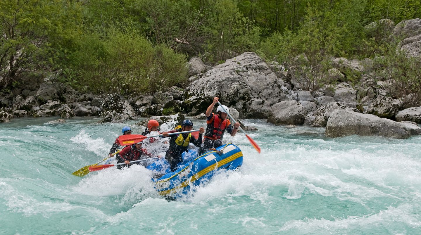 Beim Rafting auf der Saalach paddeln sechs Männer in einem Schlauchboot durchs Wildwasserr.