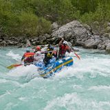 Beim Rafting auf der Saalach paddeln sechs Männer in einem Schlauchboot durchs Wildwasserr.