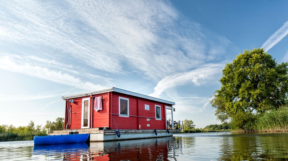 Ein rotes Hausboot schwimmt auf einem See in Brandenburg