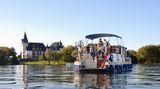 Ein Hausboot fährt auf der Müritz vor Schloss Klink vorbei