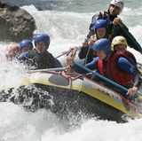 Männer und Frauen machen Rafting auf einem Wildwasser-Fluss in den Alpen