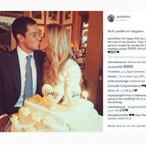 Das Brautpaar küsst sich. Im Vordergrund sieht man die sahnige Hochzeitstorte, die mit Herzen dekoriert ist.