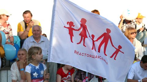 Ein Mädchen hält die neue russische Familien-Flagge in die Höhe