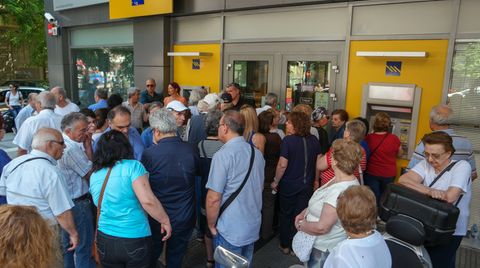 Menschen stehen vor einer geschlossenen Bank in Athen