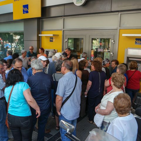 Menschen stehen vor einer geschlossenen Bank in Athen