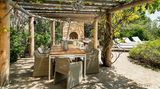 Der Außenkamin wird von einer schattenspendenden Pergola überdacht.