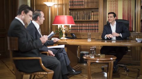 Alexis Tsipras sitzt an seinem Schreibtisch zwei Journalisten des Senders ERT gegenüber