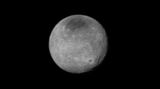 Schwarz-Weiß-Aufnahme von Charon mit dunklem Nordpol und Schluchten