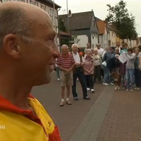 Paketzusteller Helmut Becker schaut auf 200 Demonstranten, die fordern, dass er bleiben darf