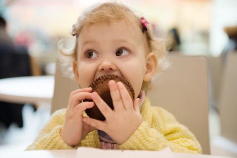 Kleines Mädchen isst einen Muffin