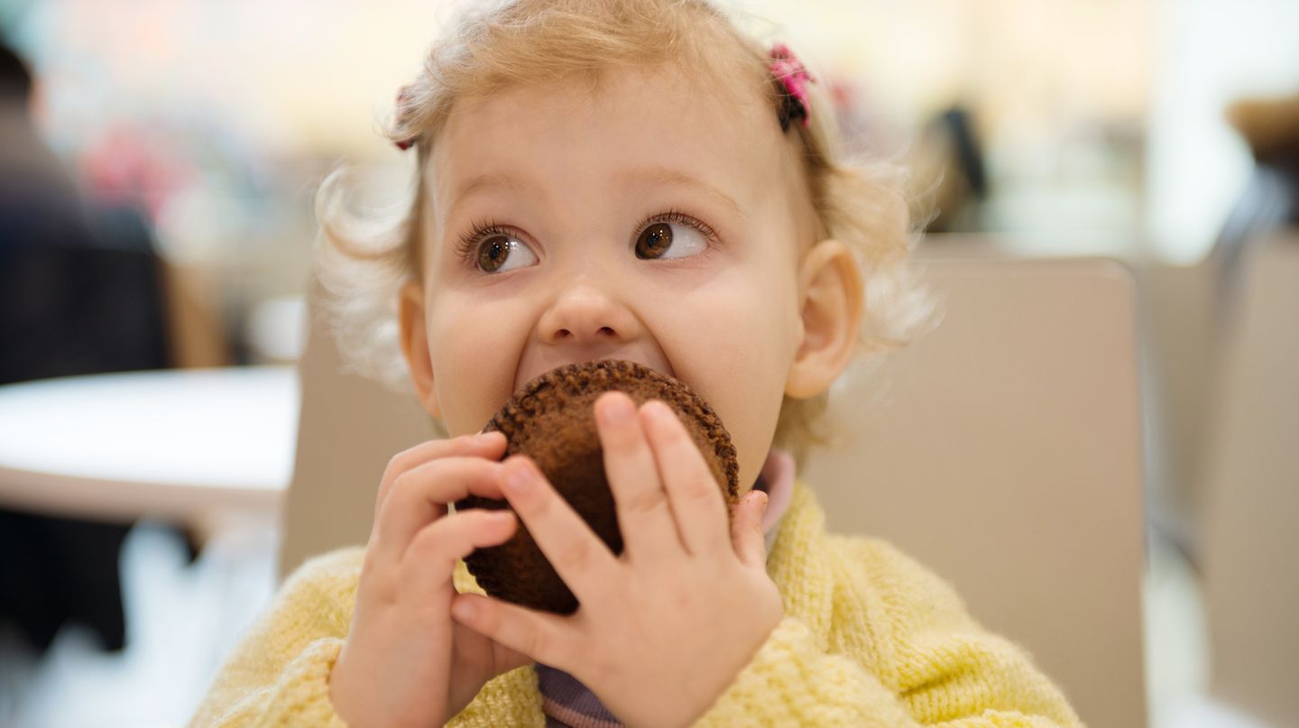 Kleines Mädchen isst einen Muffin