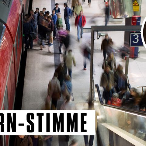 An einem Bahngleis strömen Menschen - verzerrt unkenntlich gemacht - hin und her, auf die Rolltreppe, in einen Zug hinein.