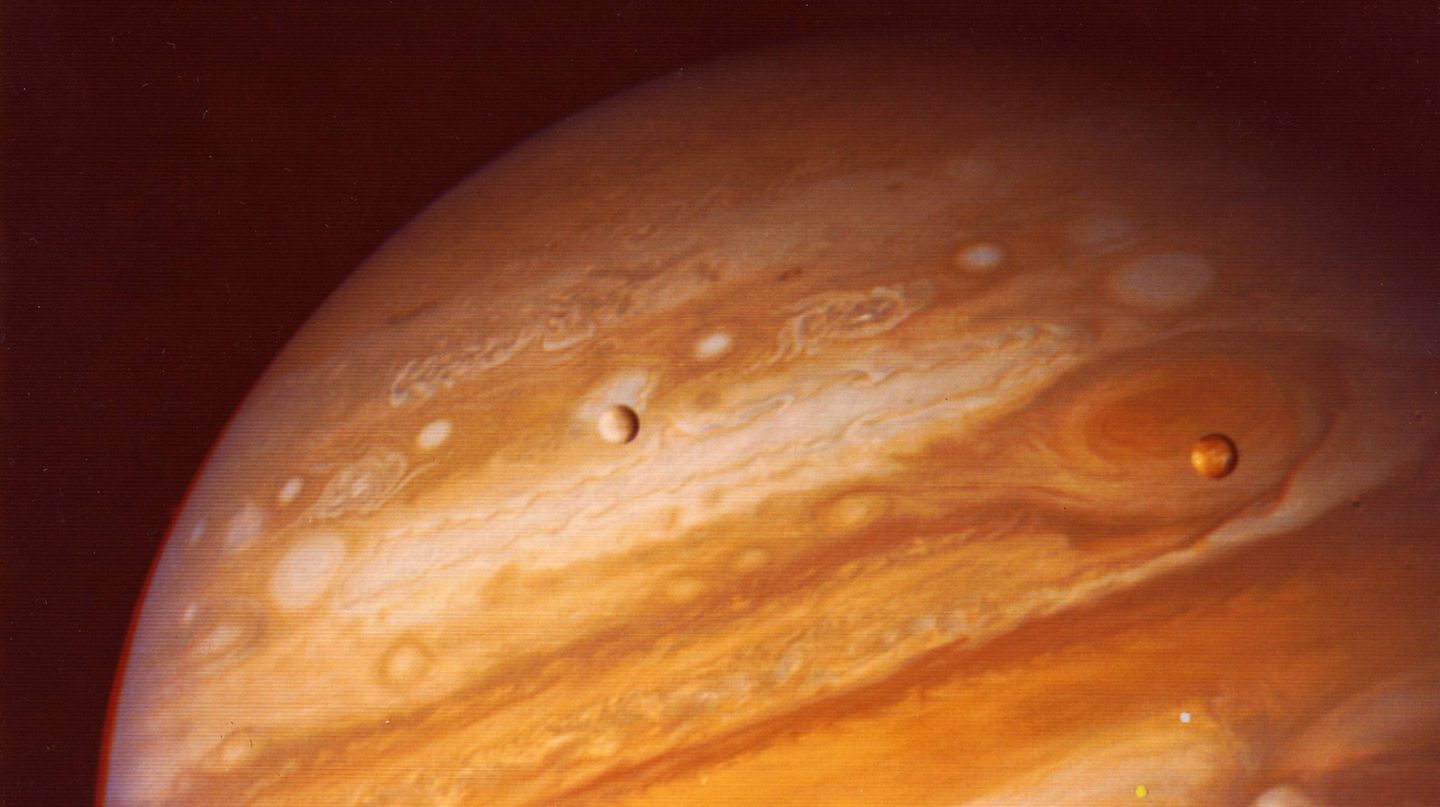 Nach New Horizons: Überall im Sonnensystem zuhause Jupiter mit dem großen Roten Fleck und den beiden Monden Io und Europa