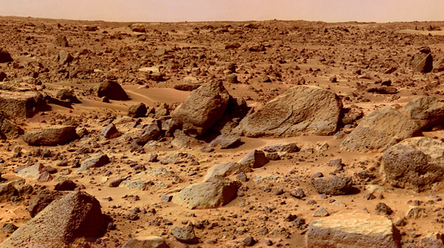 Nach New Horizons: Überall im Sonnensystem zuhause Die Marsoberfläche mit rostig-roten Steinen und Geröll. Der Himmel schimmert rötlich-braun