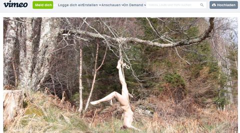 Die Künstlerin Hilde Krohn Huse hängt nackt an einem Baum