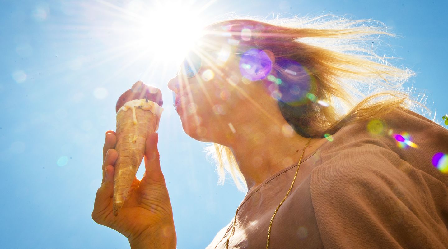Eine Frau steht im Gegenlicht der Sonne und isst ein Eis
