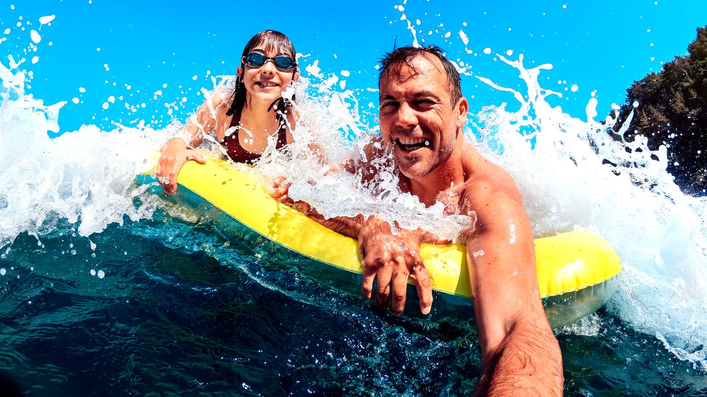 Ein Mitarbeiter sitzt mit Laptop am Strand