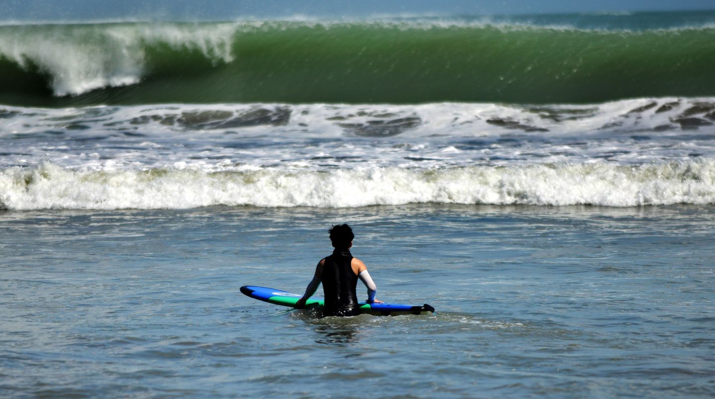 Ein Surfer wartet im Wasser auf die nächste Welle