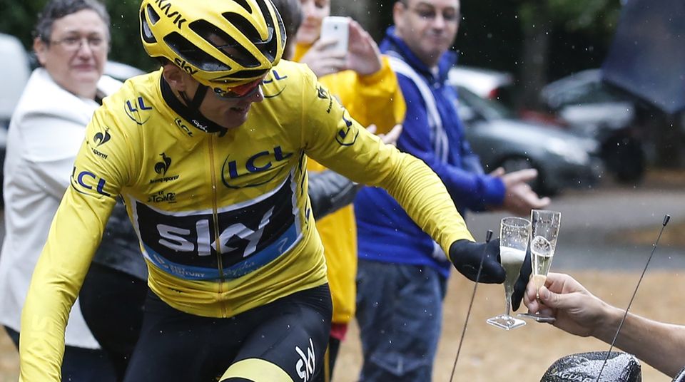 Christopher Froome, Tour de France-Sieger 2015, stößt vom Rennrad aus mit einem Glas Champagner
