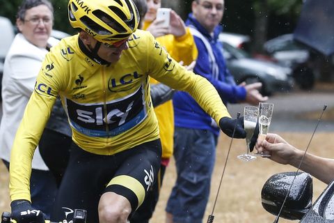 Christopher Froome, Tour de France-Sieger 2015, stößt vom Rennrad aus mit einem Glas Champagner