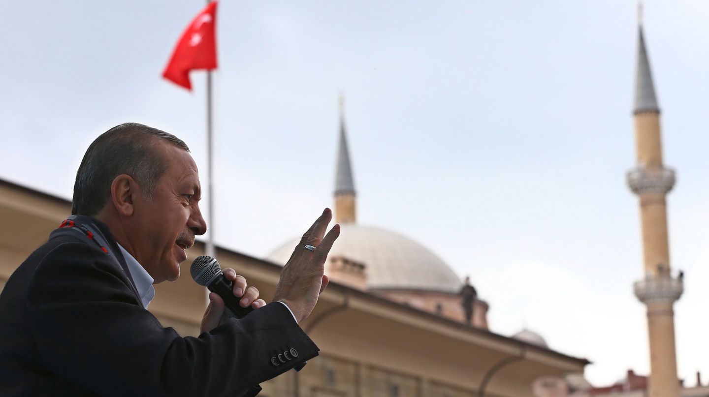 Präsident Tayyip Erdogan spricht in Eskisehir vor einer türkischen Flagge in ein Mikrofon und gestikuliert.