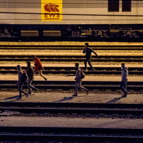 Migranten laufen entlang von Bahnschienen beim Eurotunnel-Terminal