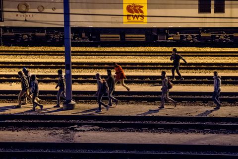 Migranten laufen entlang von Bahnschienen beim Eurotunnel-Terminal