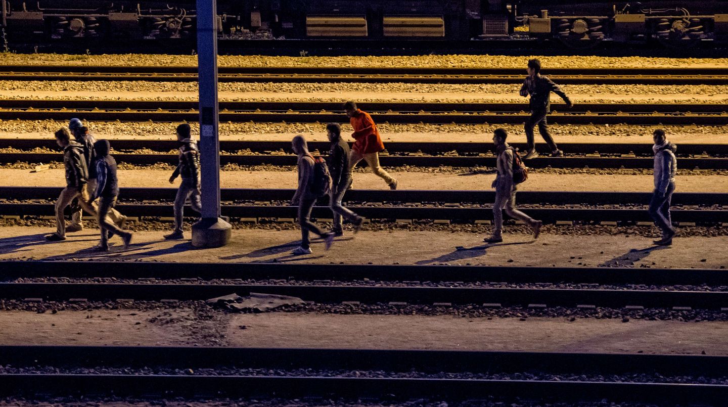 Migranten laufen entlang von Bahnschienen beim Eurotunnel-Terminal