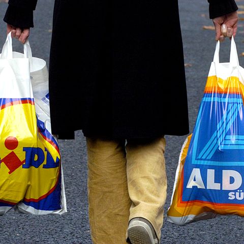 Ein Mann träge Plastiktüten von Lidl und Aldi Süd.