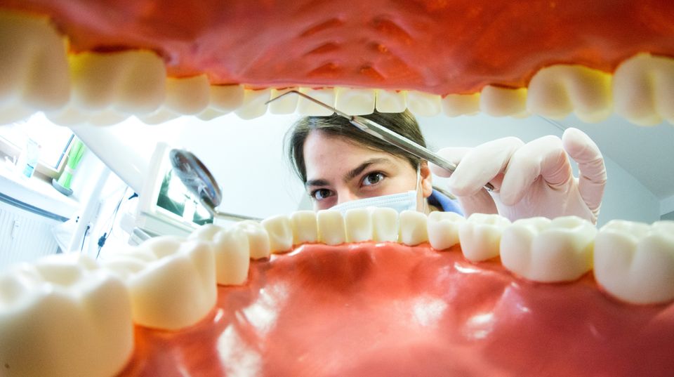 Eine Zahnärztin untersucht einen Patienten